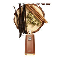 Perfume bottle with vanilla beans, cinnamon sticks, and cardamom on a wooden platform