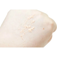 Close-up of a person's shoulder with light-colored powder on a white background