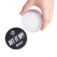Hand holding a container of W7 'Set It Up!' powder with a white background